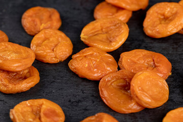 dried apricots from fresh apricots close up , dehydrated in the sun and without seeds, dried fruits on black slate