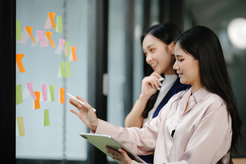 Two businesswomen standing with sticky notes on a mirror