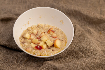 peach in oatmeal, quickly cooked oatmeal porridge with dried fruits and berries and pieces of fresh peach, closeup