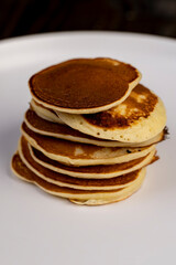 pancakes stacked together on a white bowl, a tower of small milk pancakes on a bowl, side view