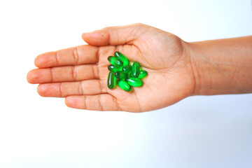 Hand Holding green Vitamin E Capsules – Health Supplement on White Background.