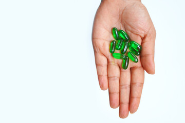 Close-Up of Hand Holding Vitamin E Capsules on Clean White Background.