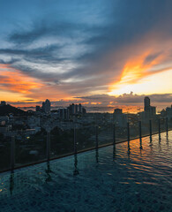 Fototapeta premium Stunning sunset over the city skyline from a rooftop pool in urban high-rise