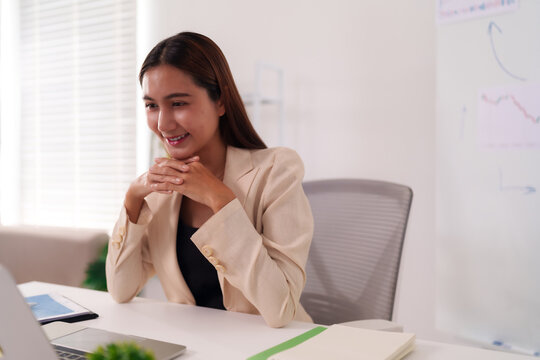 Asian businesswoman happily engaged laptop virtual meeting productive office workspace professional success digital collaboration happy entrepreneur remote work strategy