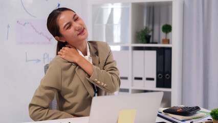 Asian business woman professional worker experience neck shoulder pain discomfort prolonged computer work office environment modern corporate desk workplace