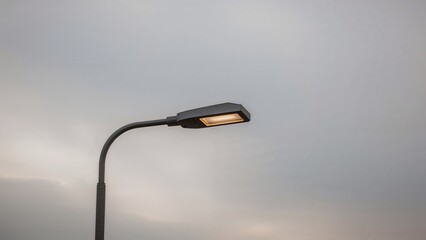 A lone streetlight with a bent arm and rectangular lamp under cloudy skies