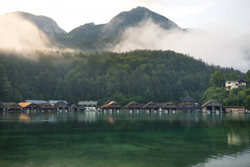 Mystischer Morgen am K&ouml;nigssee in Sch&ouml;nau mit Bootsh&auml;usern. Sonnenaufgang und sch&ouml;ne Nebelschwaden &uuml;ber dem K&ouml;nigssee im Kessel