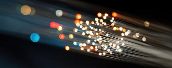 Colorful lights travel along fiber optic strands in a dark setting, showcasing technology and innovation in modern communication systems