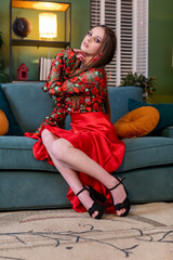 Obraz premium An Elegant Woman in a Stunning Red Dress Posing Gracefully on a Stylish and Cozy Sofa