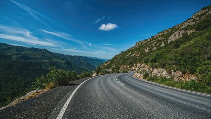 Fototapeta premium Bitumen street amid vibrant mountain scenery under a sunny cerulean sky