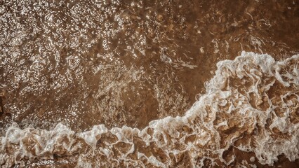 Elevated view of turbulent brown river water featuring foamy streaks