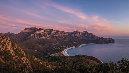 Fototapeta premium Sunset over a rugged mountain and hill scenery by the water