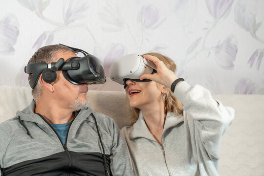 A couple in midlife joyfully dives into virtual worlds, framed by warmth, curiosity, and shared laughter. Mature Man and Woman Wearing VR glasses.