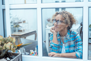 Happy middle-aged woman working on laptop at home in casual clothes, in home office or study room, smiling while using technology, enjoying smart working, remote work, online business and productive l