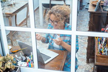 Happy middle-aged woman working on laptop at home in casual clothes, in home office or study room,...