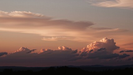 Obraz premium Enchanting sunset backdrop with fluffy clouds and warm pastel tones