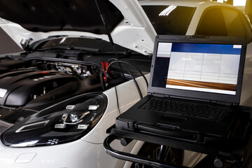 Obraz premium Mechanic use laptop near car engine. Modern car diagnostic program on screen. Car service concept.