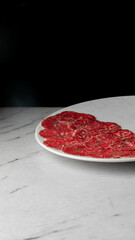 Sliced salami on marble whispers culinary tales, ideal for charcuterie aficionados, invoking Salami Day's savory indulgence