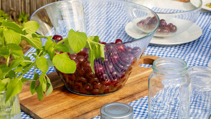 Glistening cherries in a glass bowl evoke rustic summer picnics, surrounded by nature's green bounty, perfect for Cherry Blossom Festival feasts