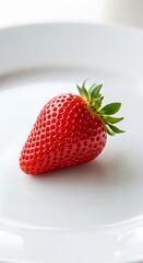 Single, vibrant red strawberry on a white plate.