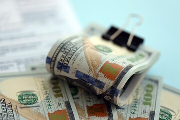 Big amount of United States USD dollar bills on table with 1040 tax return form