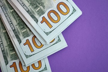 Big amount of United States hundred dollar bills on purple background