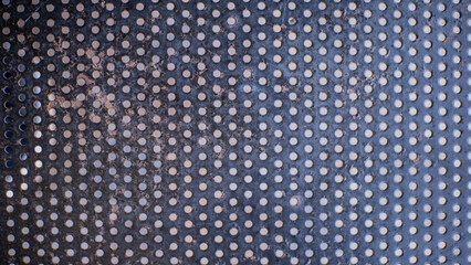 Close-up of perforated metal sheet with evenly spaced round holes and textured surface detail