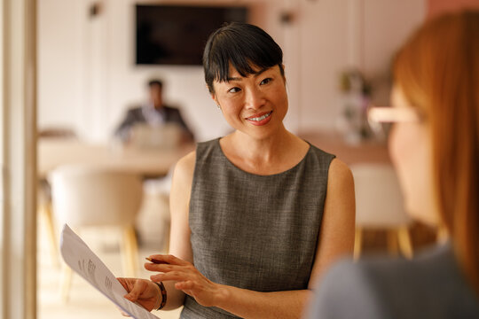 Confident manager reviewing reports and brainstorming ideas with female partner in collaborative workspace - Powered by Adobe