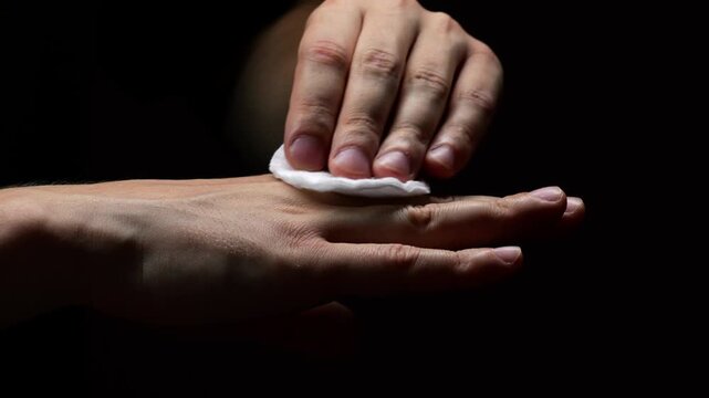 A man wipes his hands with a cotton swab and disinfects the problematic area on his hand.
Disinfection of hands and hygiene.
Hand treatment with alcohol solution or chlorhexidine