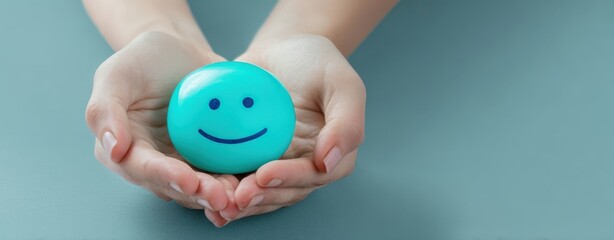 The hands gently holding a cheerful blue smiley face stone decoration.