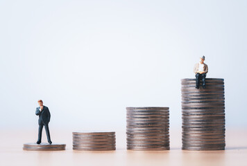 Miniature figure young businessman standing and Senior Pensioners sitting on the top coins stacking...