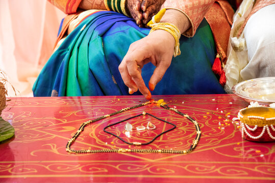A close-up of the traditional Mangalsutra Pujan ritual performed during a Maharashtrian wedding, featuring the sacred mangalsutra necklace being blessed with turmeric and other symbolic offerings.