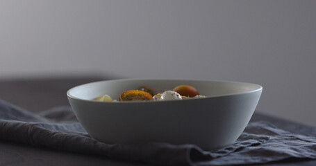 put kumato tomatoes on fettuccine in white bowl on linen cloth