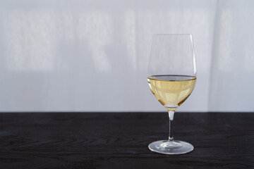 White wine in a wineglass on black oak table with copy space
