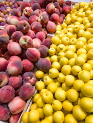 Vibrant display of ripe peaches and plums at local market during summer afternoon