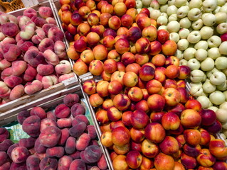 Fresh produce display with vibrant apples and peaches at a market showcasing colorful fruits during a busy afternoon