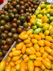 Colorful display of fresh tomatoes in a market stall showcasing a variety of shapes and colors during a sunny day
