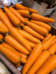 Fresh carrots arranged neatly in a wooden crate at a local market during a sunny afternoon
