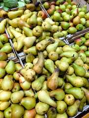 Fresh variety of green and yellow pears displayed in wooden crates at a vibrant local market during the autumn harvest season