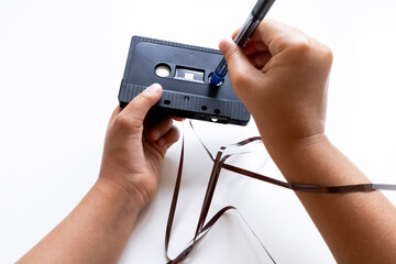 Child adjusting cassette tape ribbon with pencil in hands
