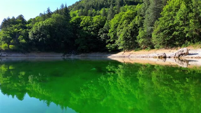 Aerial drone view of Lake San Domenico in the municipality of Villalago in the province of L'Aquila, near the hermitage of San Domenico. Beautiful green hues and peace reign supreme in this place.
