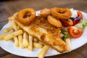 Fish and Chips salad with fried onion ring, served on plate