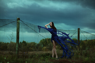 A stunning Ethereal Woman dressed in Blue stands beautifully against a dramatic Stormy Sky