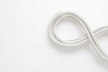 Minimalist composition: coiled electric cable forming the shape of an infinity symbol on clean white background