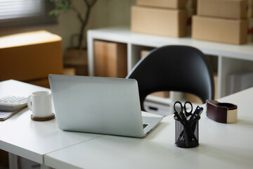 Online merchant's work desk with laptop placed on it, front view