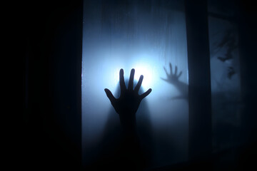 Dark silhouette of hand behind glass in supernatural light. Locked alone in room behind door on Halloween. Nightmare of kid with aliens, monsters and ghosts. Evil in home. Сhild inside haunted house.