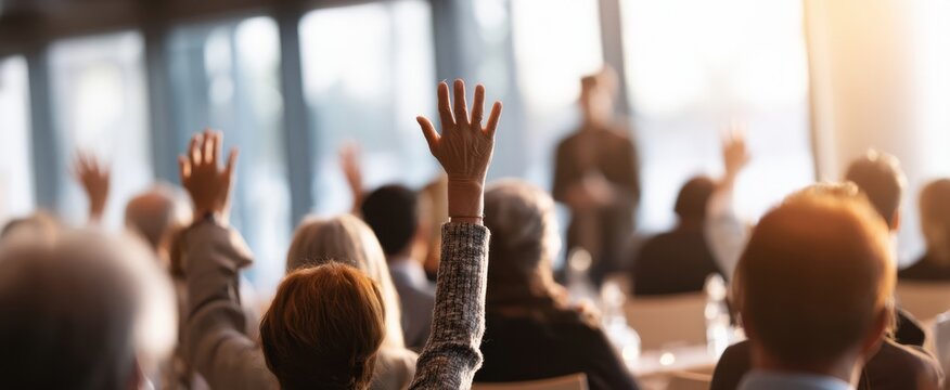 The engaged audience raising hands during an interactive presentation at a conference