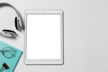 Tablet, stationery, headphones and glasses on white background, flat lay. Space for text