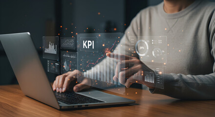 Person working on a laptop, interacting with a virtual "KPI" dashboard displaying various data charts and graphs. Perfect for business analysis and performance.