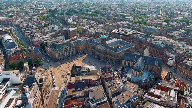 4K aerial of Amsterdam&rsquo;s Dam Square with the Royal Palace and Nieuwe Kerk, tram lines and crowds, surrounded by historic gabled roofs - iconic view of the Dutch capital&rsquo;s old town.